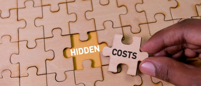 Hand placing a puzzle piece labelled hidden costs into an incomplete puzzle, symbolising unseen challenges in relocation and global mobility programmes.