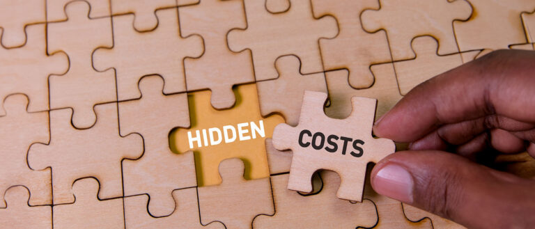 Hand placing a puzzle piece labelled hidden costs into an incomplete puzzle, symbolising unseen challenges in relocation and global mobility programmes.